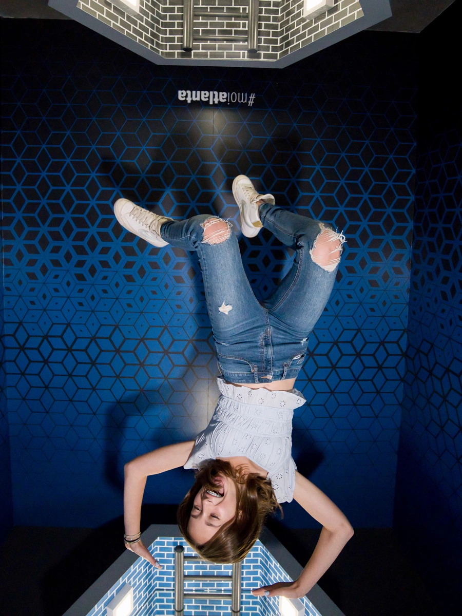 A woman looks like she's falling head down through the Infinity Portal at Museum of Illusions Atlanta.